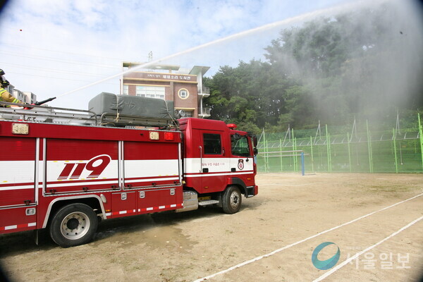 (사진/고영준기자) 광주 동부소방서 소속 지산 펌프차가 학교 밖 숲에서 산불이 발생한 상황을 가정하여 방수를 진행하고 있다.